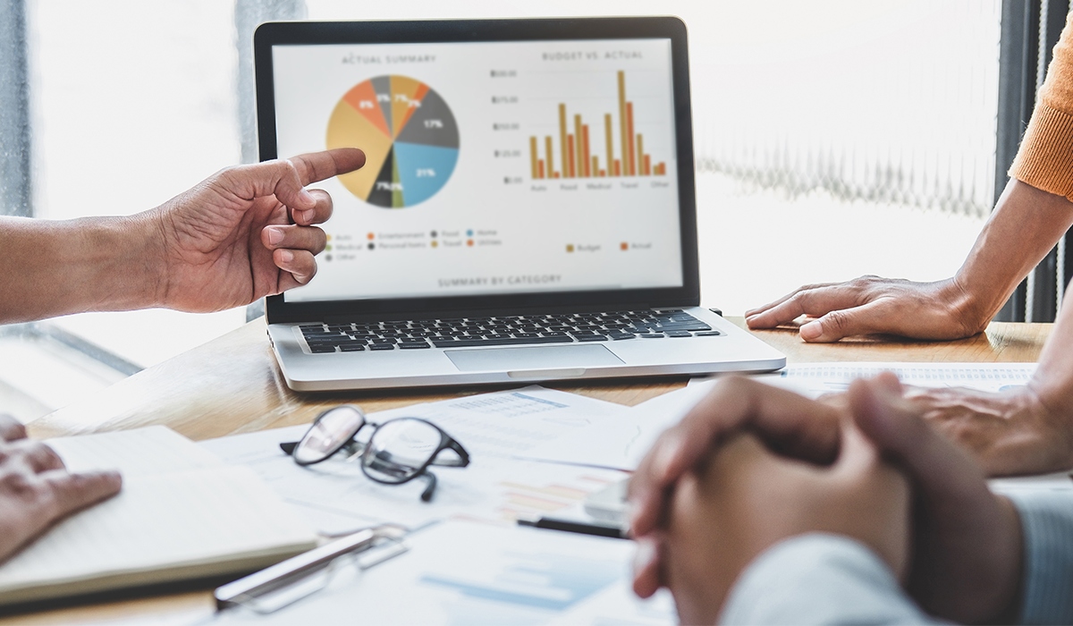 Hand pointing at screen with data displayed in charts